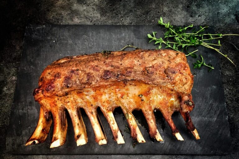 Delicious grilled spare ribs served with fresh herbs on a stone surface.